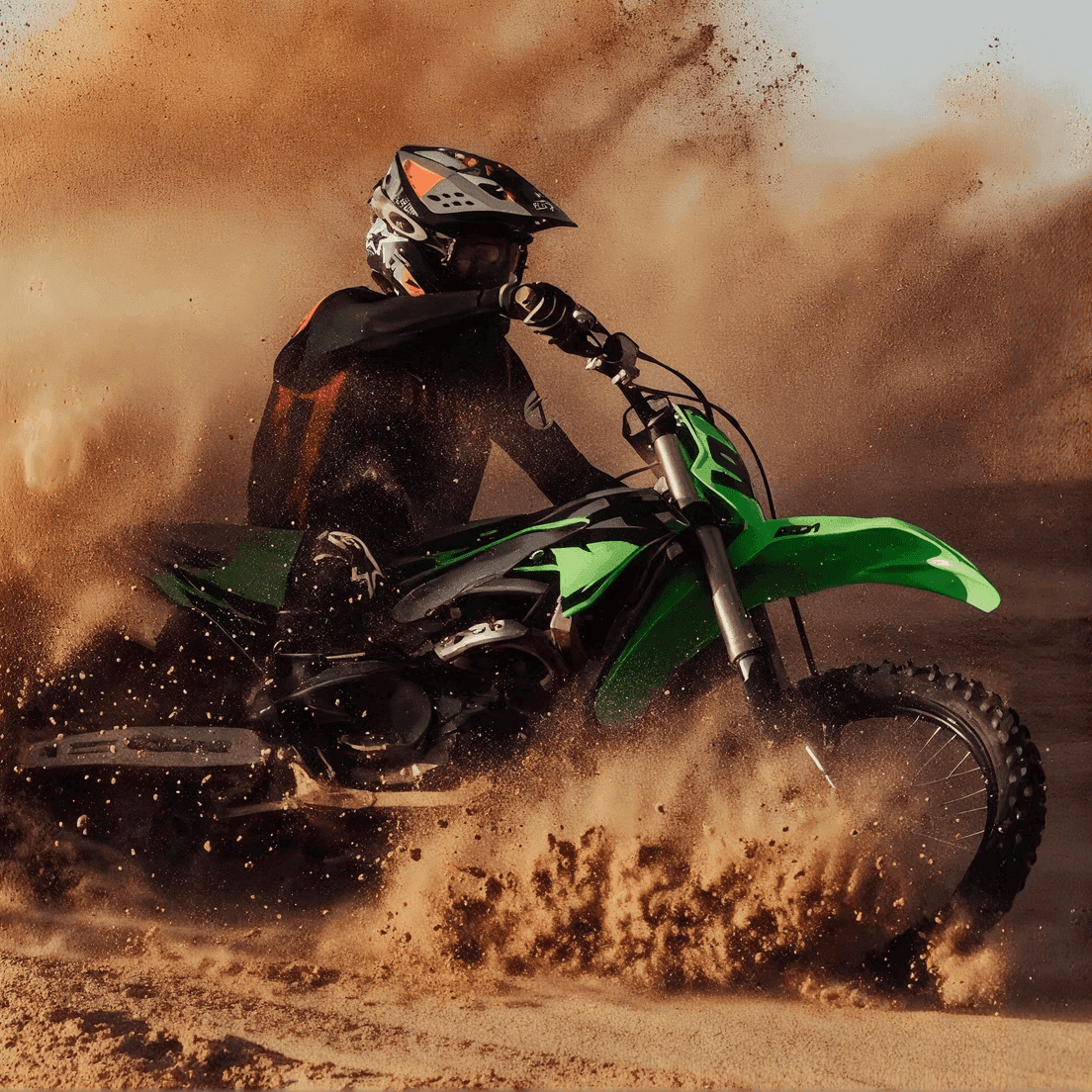 Un piloto de motocross levantando arena y polvo con una moto todoterreno verde en un giro brusco.